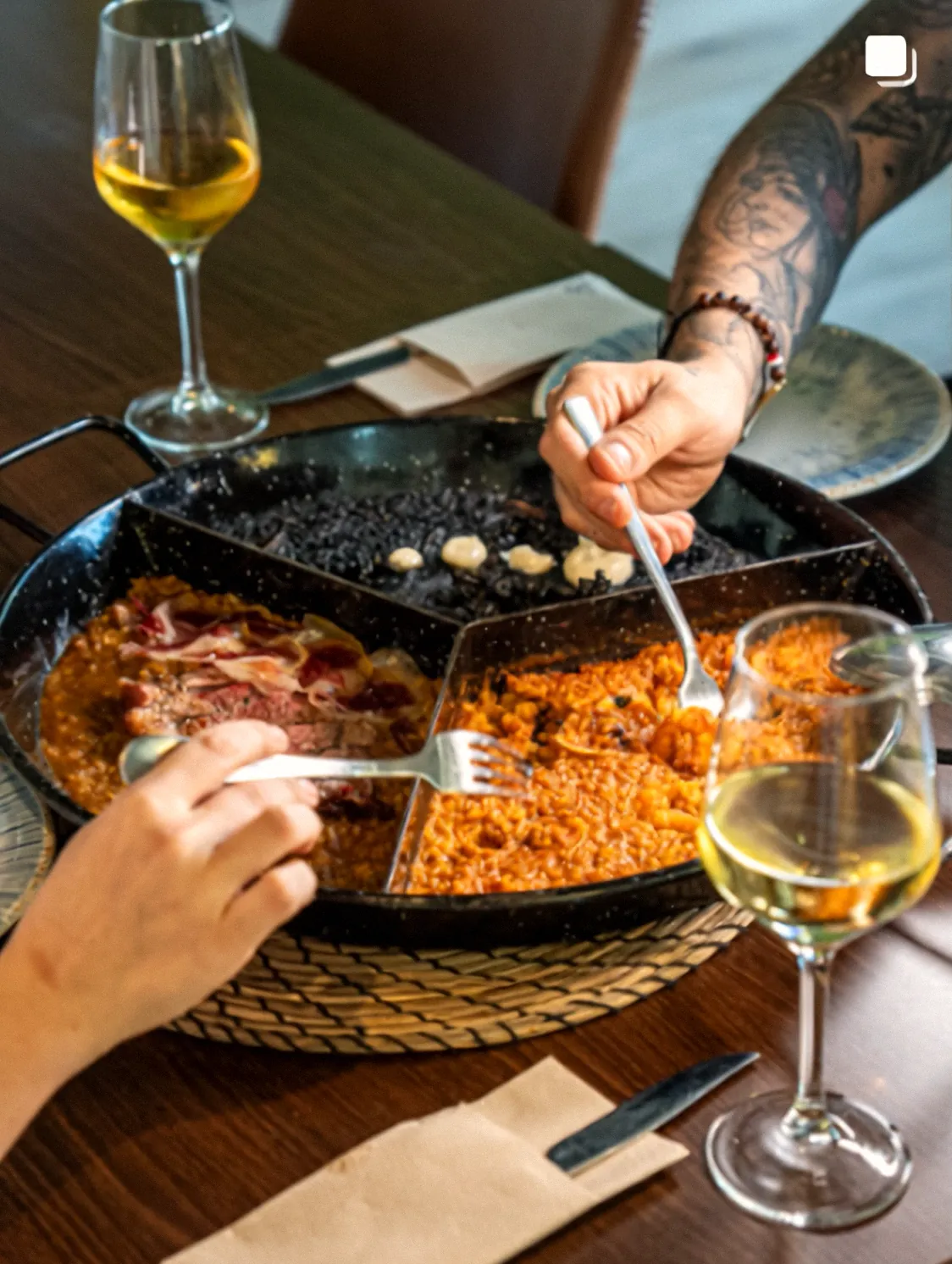 Comensales sirviéndose del trío de arroces con vino blanco