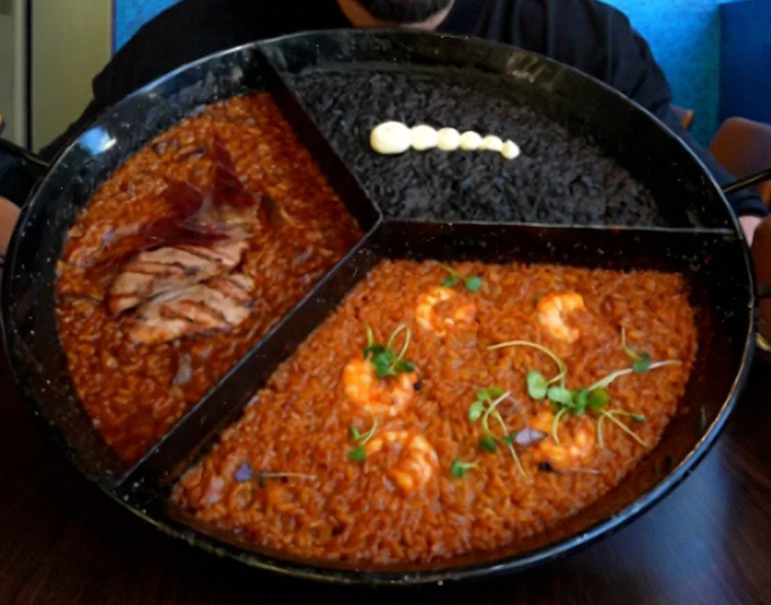 Paellera del trío de arroces dividida en tres: ibérico, negro con alioli y marinero con gambas